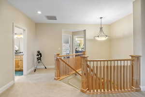 Hallway with visible vents, baseboards, recessed lighting, carpet flooring, and an upstairs landing