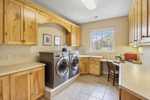 Laundry room featuring light tile patterned floors, visible vents, cabinet space, and washer and dryer