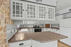 Kitchen with crown molding, a sink, white appliances, a peninsula, and decorative backsplash