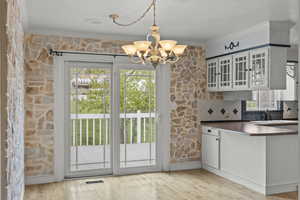Kitchen with dark countertops, a notable chandelier, ornamental molding, and a healthy amount of sunlight