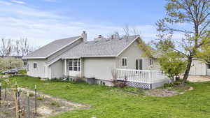 Back of property featuring a shingled roof, a storage shed, a wooden deck, a chimney, and a yard
