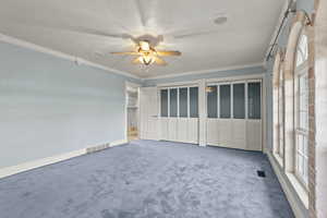 Spare room with visible vents, a ceiling fan, a healthy amount of sunlight, and ornamental molding
