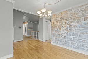 Unfurnished dining area with baseboards, an inviting chandelier, ornamental molding, and wood finished floors