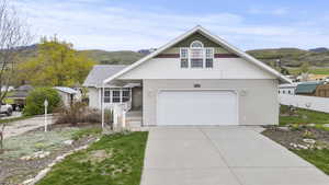 Traditional home with an attached garage, a mountain view, driveway, and fence