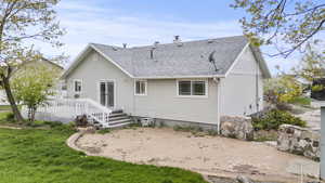 Back of house featuring roof with shingles, a wooden deck, a chimney, a patio area, and a yard