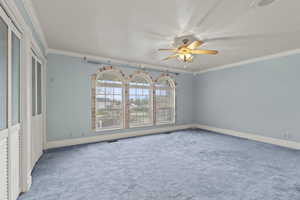 Unfurnished room with ceiling fan, visible vents, crown molding, baseboards, and carpet