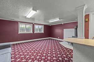 Unfurnished office with carpet floors, a textured ceiling, visible vents, and a wood stove