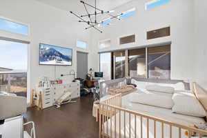 Bedroom featuring a high ceiling, an inviting chandelier, and wood finished floors