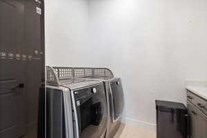 Laundry area featuring baseboards, cabinet space, washer and dryer, and light tile patterned floors
