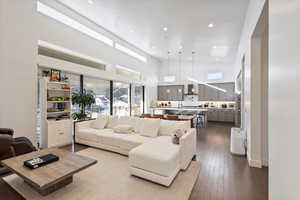 Living room with a high ceiling, recessed lighting, and dark wood-style flooring