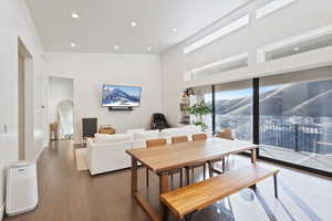 Dining area with a high ceiling, recessed lighting, arched walkways, and wood finished floors