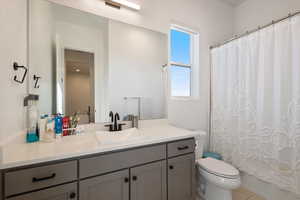 Bathroom featuring toilet, shower / tub combo with curtain, and vanity