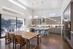 Dining room with a wealth of natural light, a towering ceiling, and dark wood finished floors