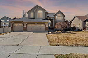 View of front of house with driveway, stucco siding, fence, and brick siding