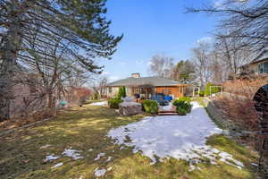 Back of property with a lawn, a chimney, a wooden deck, and brick siding