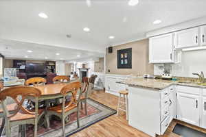 Dining area with light wood finished floors, a wainscoted wall, and recessed lighting