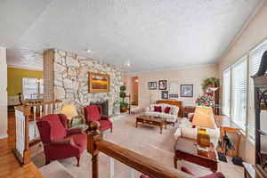 Living room with a textured ceiling, a fireplace, wood finished floors, and ornamental molding
