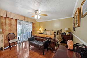 Bedroom featuring a textured ceiling, wood finished floors, ceiling fan, and crown molding