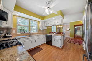 Kitchen featuring white cabinets, light wood-style flooring, a peninsula, stainless steel appliances, and a sink