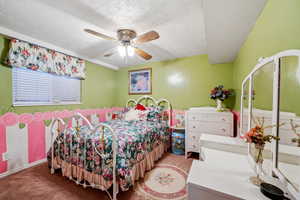 Carpeted bedroom featuring ceiling fan and a textured ceiling