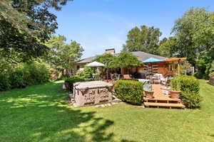 View of green lawn with a wooden deck and a hot tub