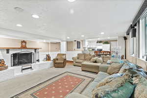 Carpeted living area with a brick fireplace, recessed lighting, and wainscoting