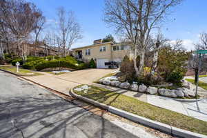 View of front of property featuring a chimney, an attached garage, and concrete driveway