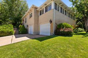 View of side of property with an attached garage, driveway, and a yard