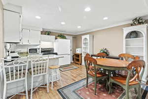 Dining area with crown molding, light wood-type flooring, and recessed lighting