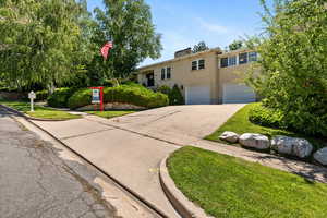 View of front of property featuring concrete driveway, a garage, brick siding, and a chimney