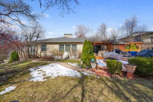 Back of property with a chimney, brick siding, and a lawn