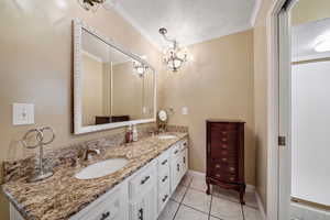Full bath with tile patterned flooring, crown molding, baseboards, a sink, and double vanity