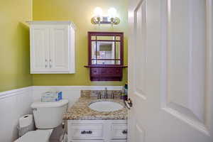 Bathroom with toilet, vanity, and wainscoting