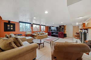 Living room featuring light colored carpet, a fireplace, recessed lighting, and a textured ceiling