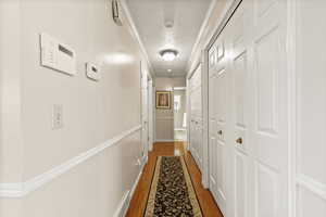 Hallway featuring crown molding, a textured ceiling, and wood finished floors