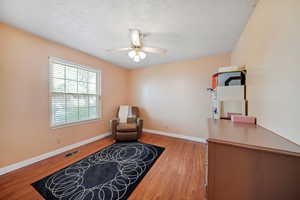 Sitting room featuring baseboards, visible vents, light wood-style flooring, and a ceiling fan