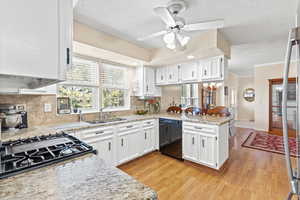 Kitchen featuring dishwasher, a peninsula, white cabinets, light wood-type flooring, and a textured ceiling