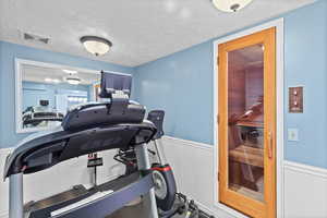 Workout area featuring a wainscoted wall and a textured ceiling