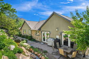 Back of house featuring a patio, stone siding, stucco siding, french doors, and a shingled roof