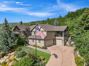 View of front facade featuring stucco siding, a balcony, stone siding, an attached garage, and concrete driveway