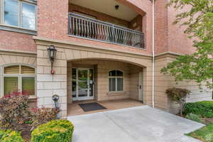 Property entrance featuring a balcony, brick siding, and french doors