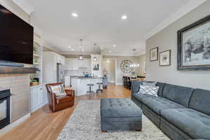 Living room with baseboards, crown molding, light wood-style floors, and recessed lighting