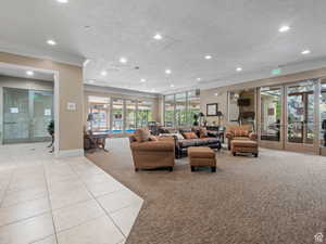Living area featuring a textured ceiling, recessed lighting, light tile patterned floors, and ornamental molding