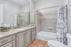 Bathroom featuring vanity, toilet, shower / tub combo, and wood finished floors