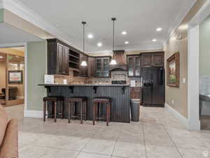 Kitchen featuring crown molding, dark brown cabinetry, black refrigerator with ice dispenser, glass insert cabinets, and custom exhaust hood