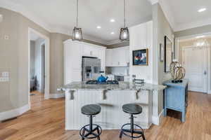 Kitchen with light wood finished floors, visible vents, light stone counters, and appliances with stainless steel finishes