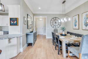 Dining area featuring ornamental molding, baseboards, and light wood-type flooring
