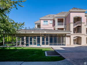 Rear view of house featuring a sunroom, a patio area, brick siding, and a yard