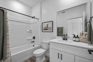 Full bathroom featuring shower / bathtub combination with curtain, vanity, toilet, visible vents, and wood finished floors