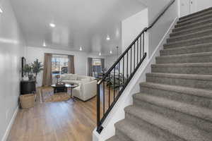 Stairway featuring baseboards, wood finished floors, and recessed lighting